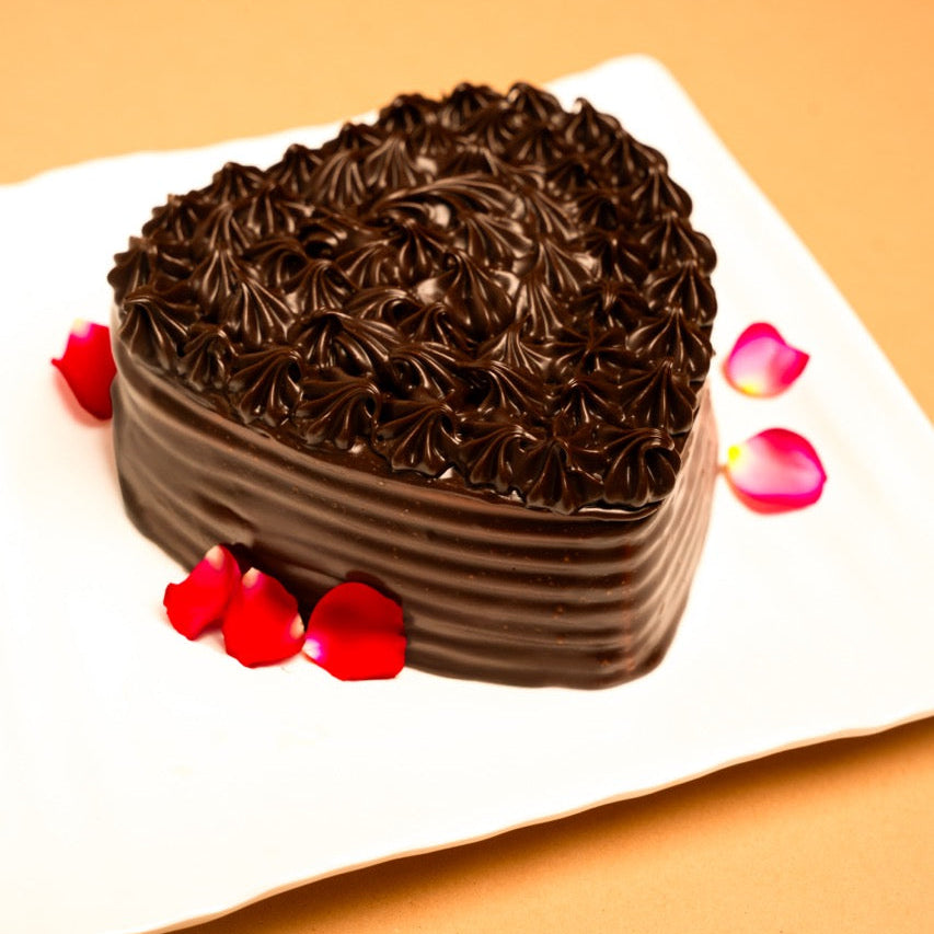 Chocolate cake on a white plate with red flowers on a beige background